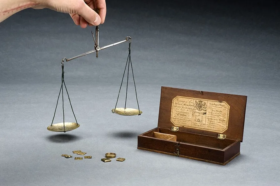 손에 든 앤티크 양팔 저울과 작은 분동 사진으로, 롱 계좌 수와 숏 자금 규모가 서로 균형을 이루는 원리를 표현한 이미지